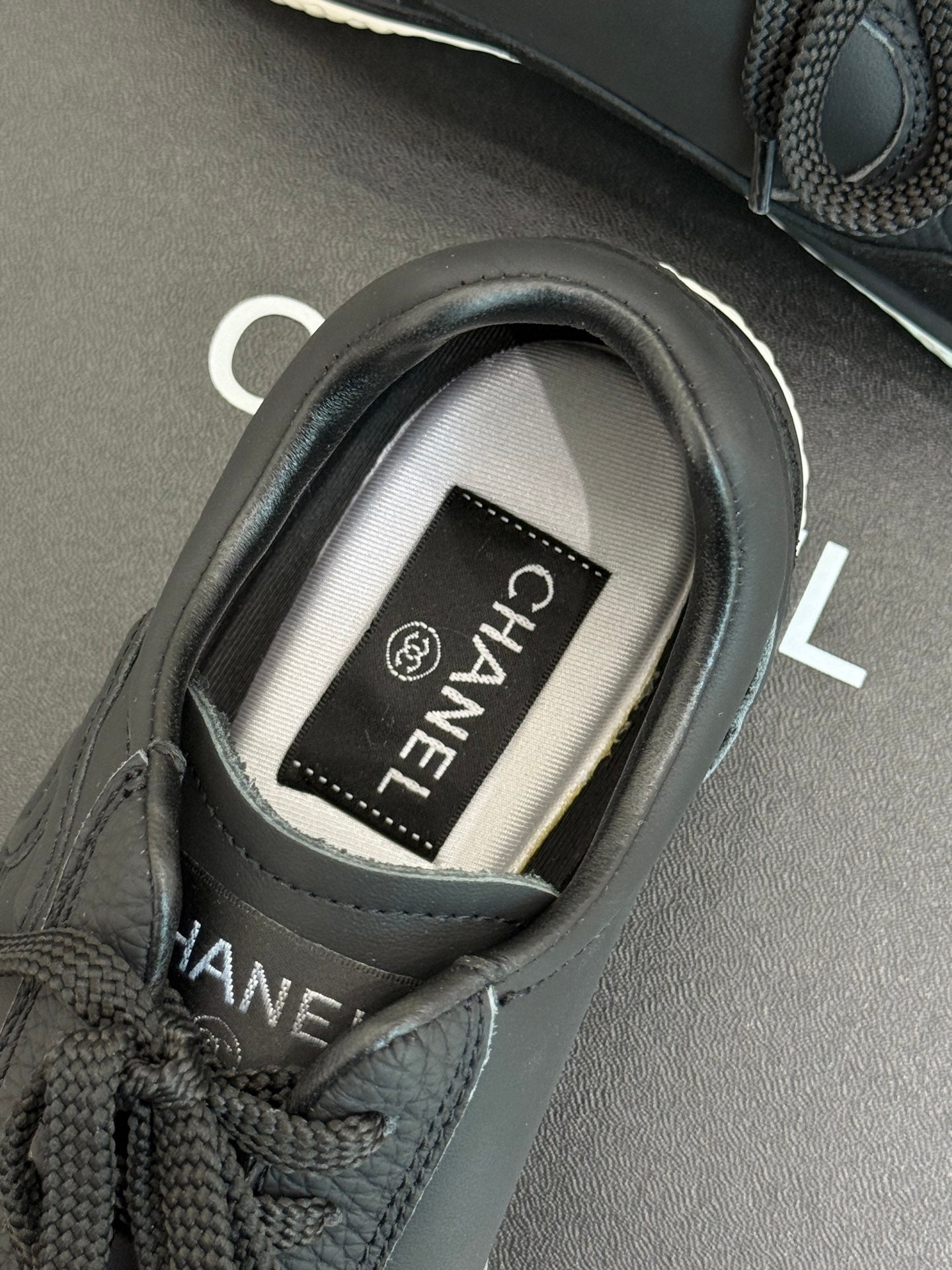 Close-up of dark sneaker with CHANEL label inside the collar