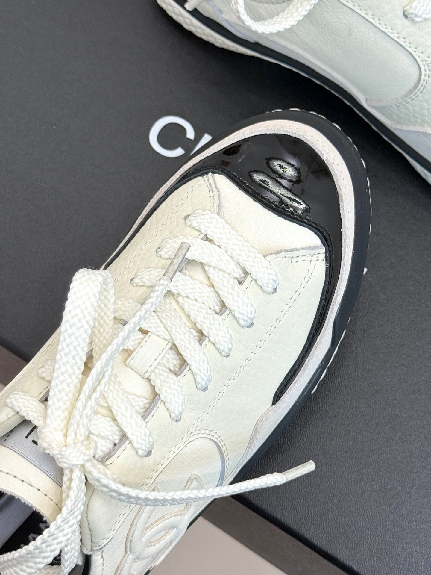 Close-up white sneaker with black-trimmed sole and white laces
