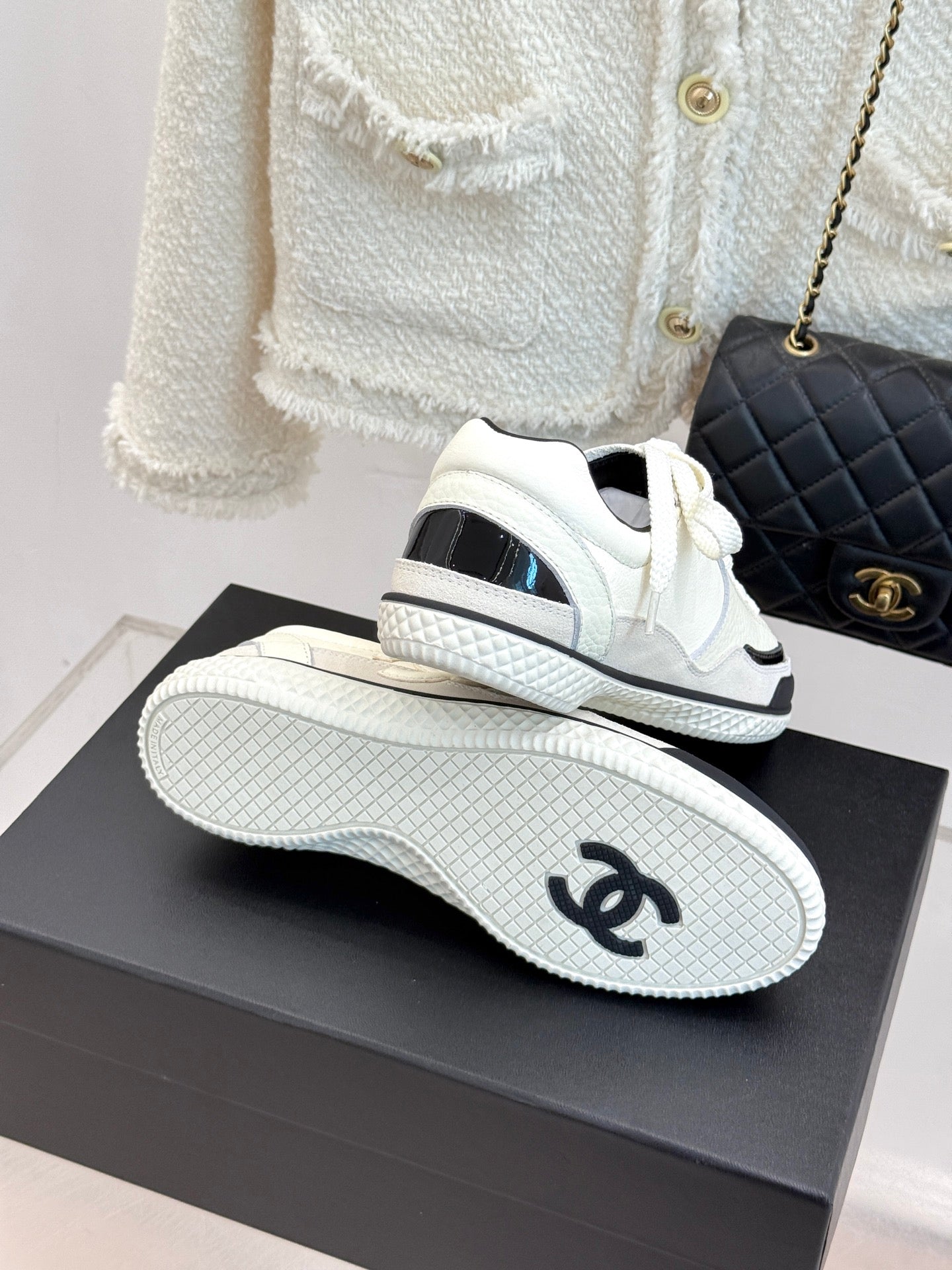 White low-top sneakers with black sockliners and textured tread soles
