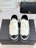 White low-top sneakers with black toe caps, white laces, and black sole trim