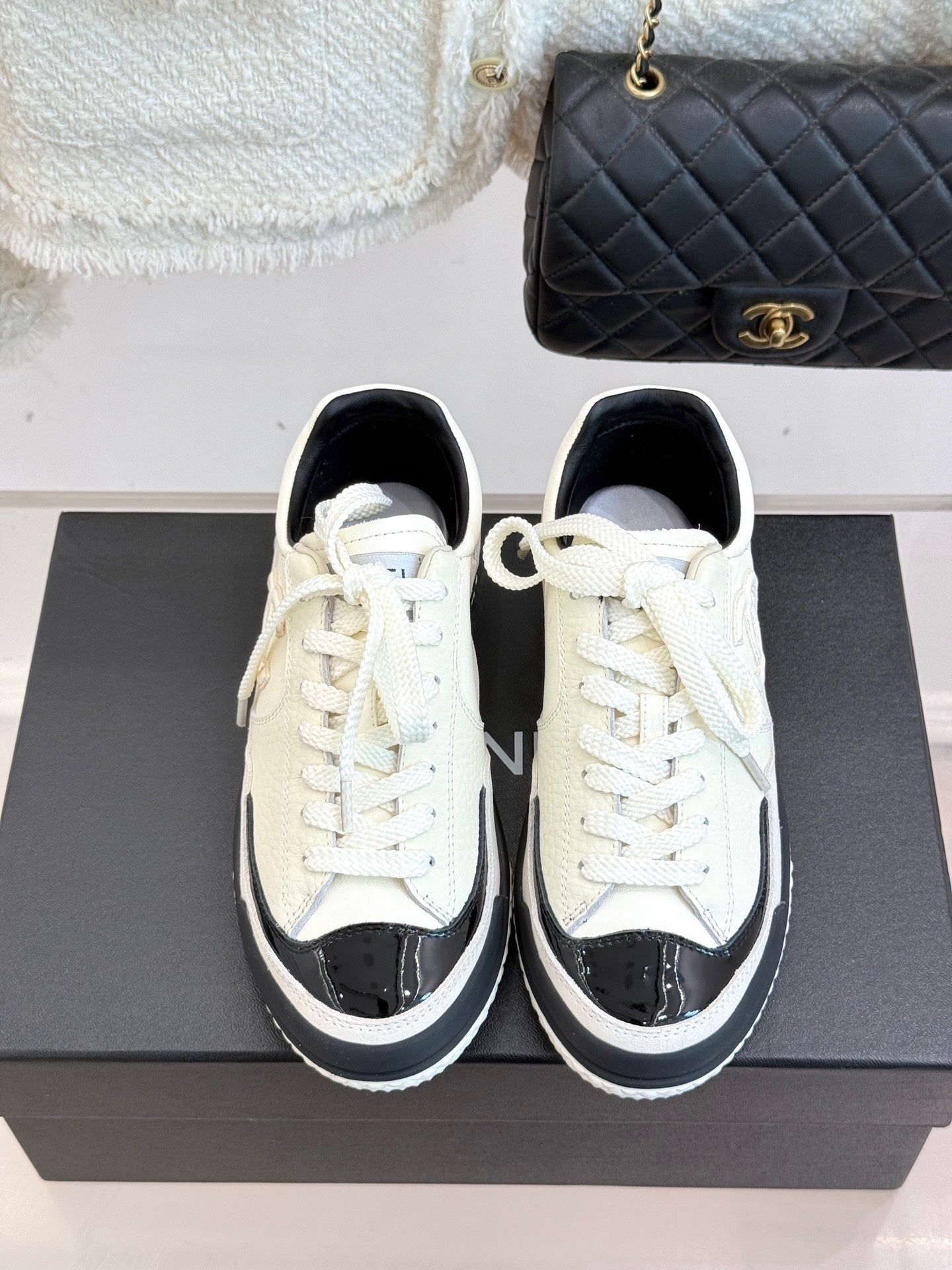 White low-top sneakers with black toe caps, white laces, and black sole trim