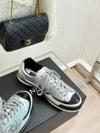 Metallic silver sneakers with black-trim soles and lace-up uppers, placed on a box