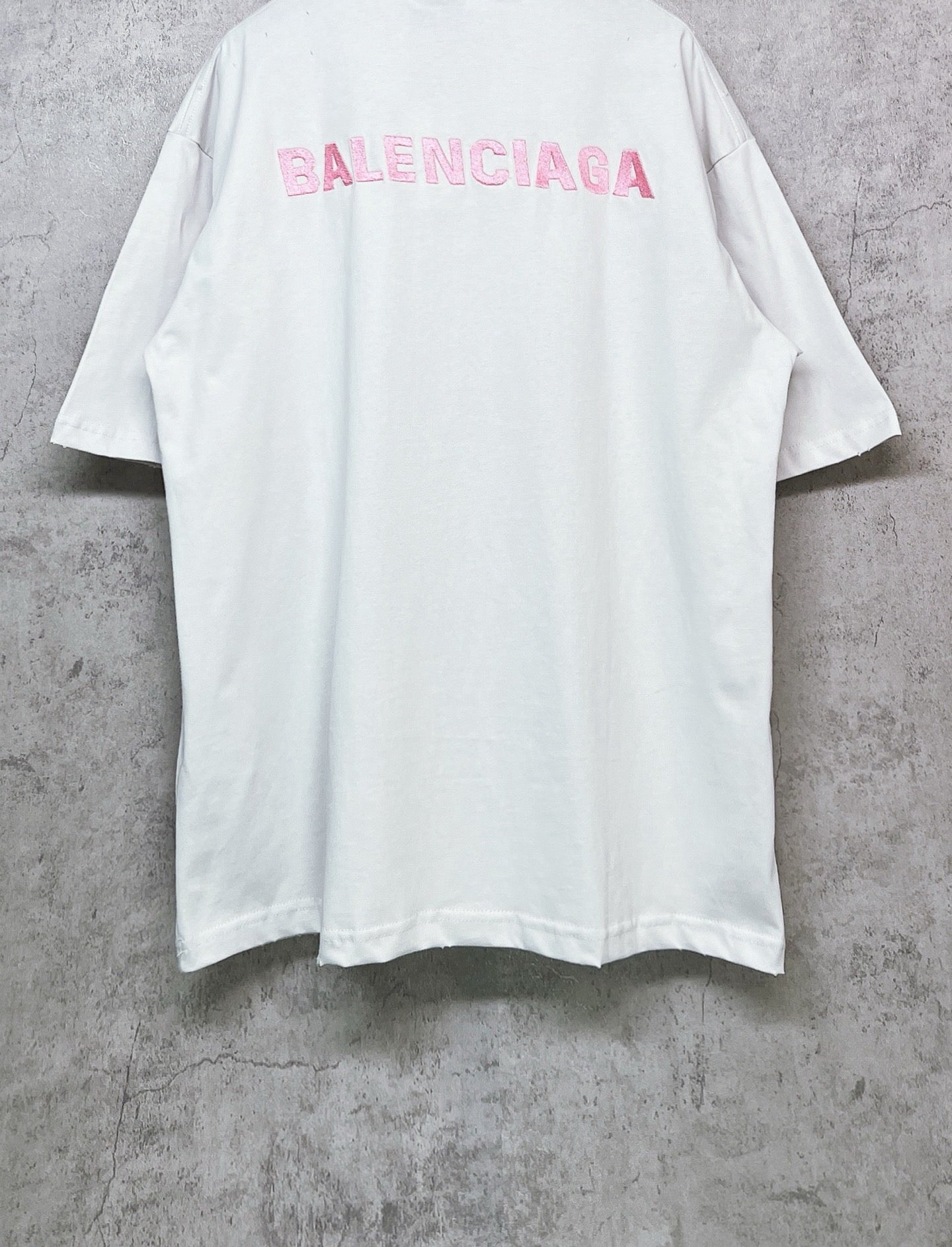 White short-sleeve crewneck T-shirt with pink BALENCIAGA logo on upper back