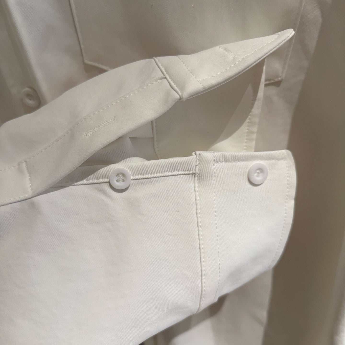 White long-sleeve shirt with buttoned cuff and side seam detail