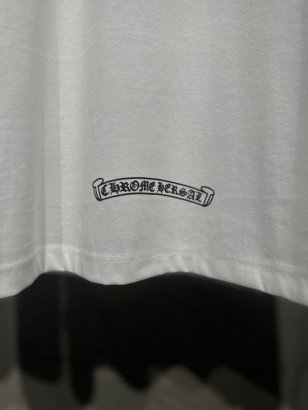 White raglan shirt back hem, small outlined text logo near bottom