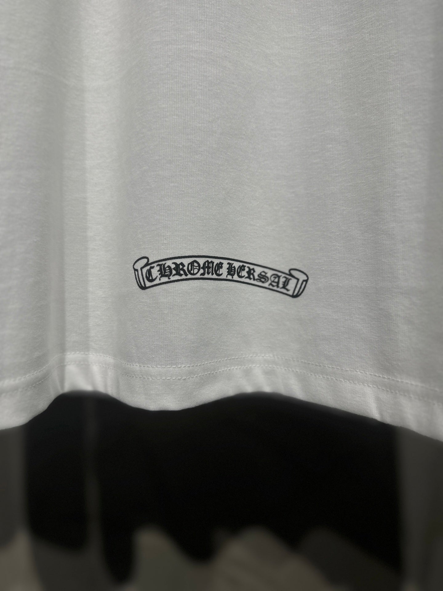 White raglan shirt back hem, small outlined text logo near bottom