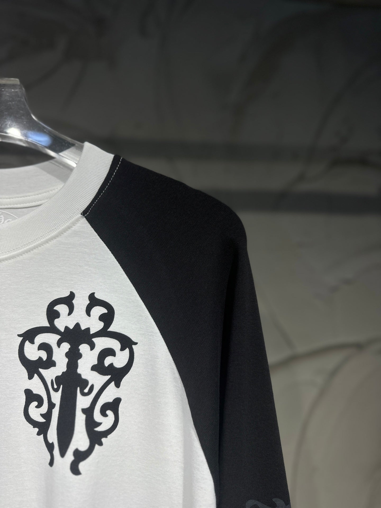 White raglan shirt with black sleeve, large ornamental cross graphic