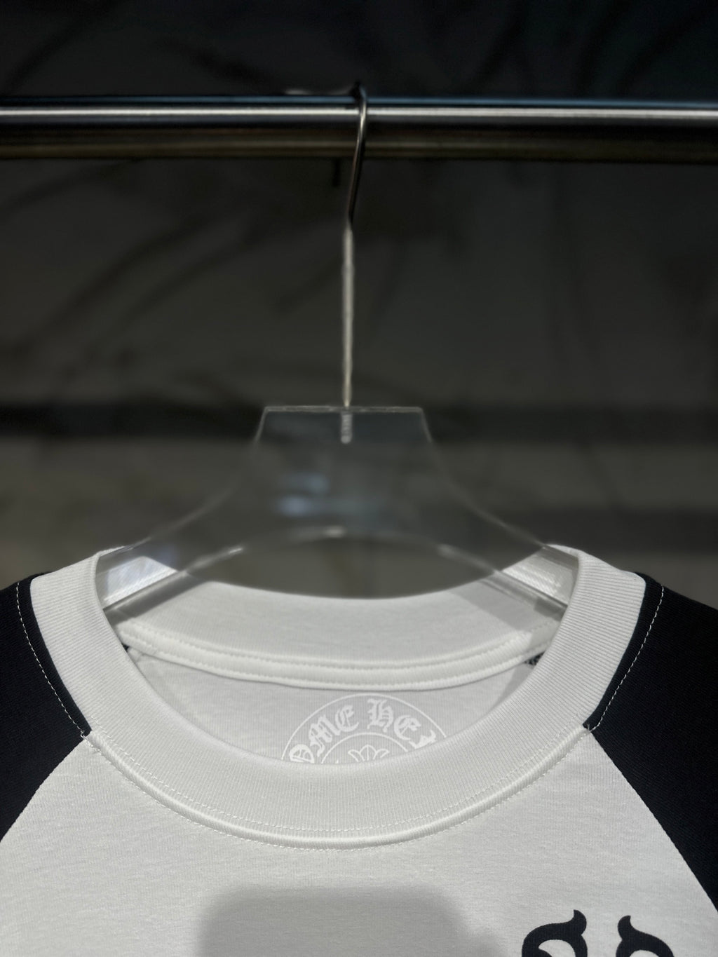 White crew-neck raglan shirt, black collar trim, small chest emblem