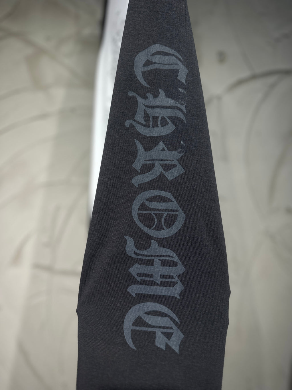 Black raglan sleeve with vertical dark lettering graphic