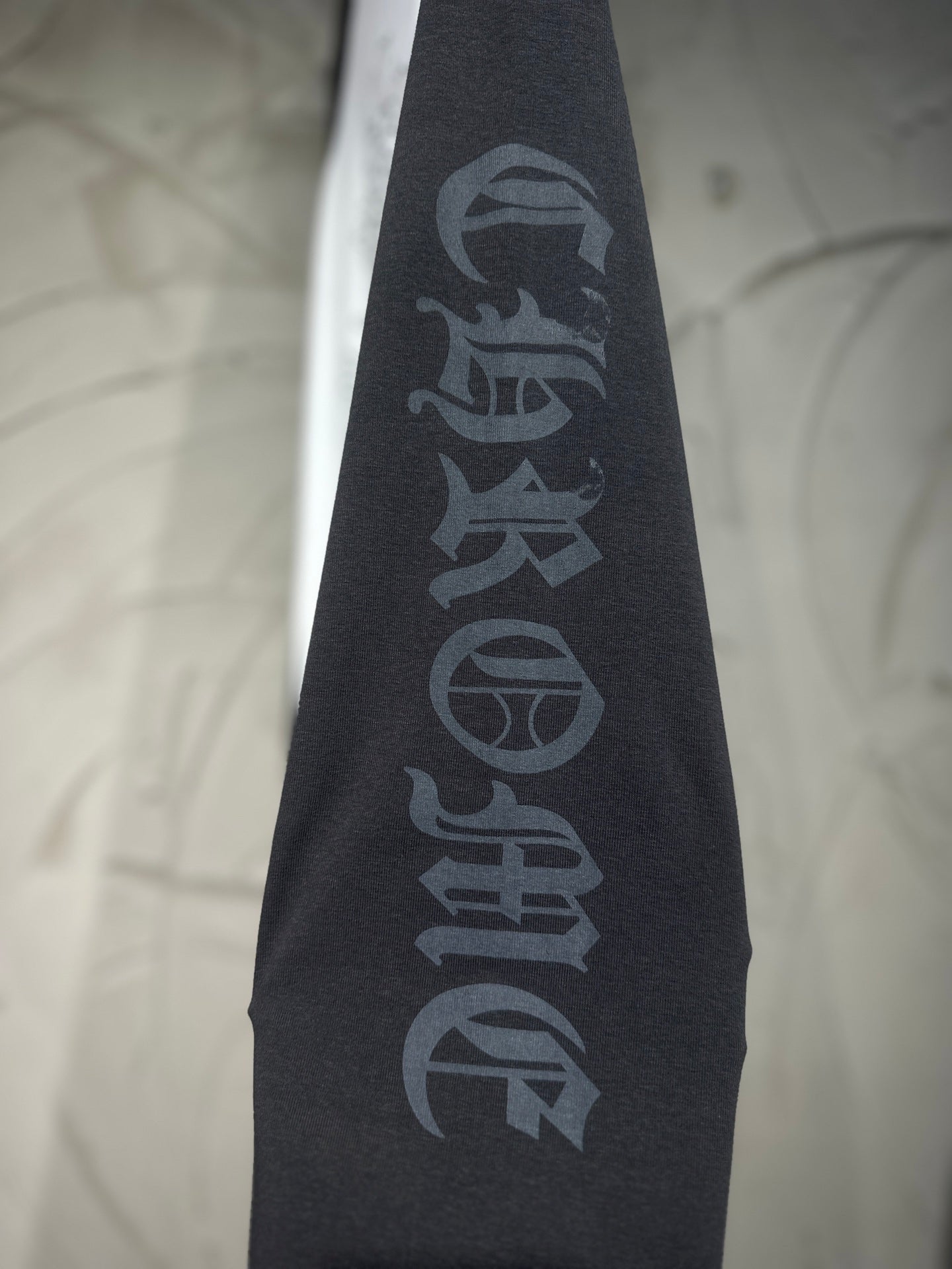 Black raglan sleeve with vertical dark lettering graphic