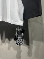 White raglan shirt with black sleeve, decorative hang tag near bottom