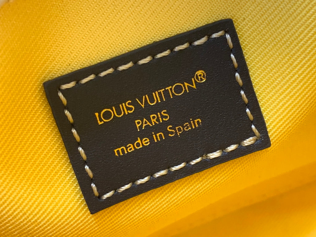 Black leather label with gold “Louis Vuitton Paris” text on yellow interior lining