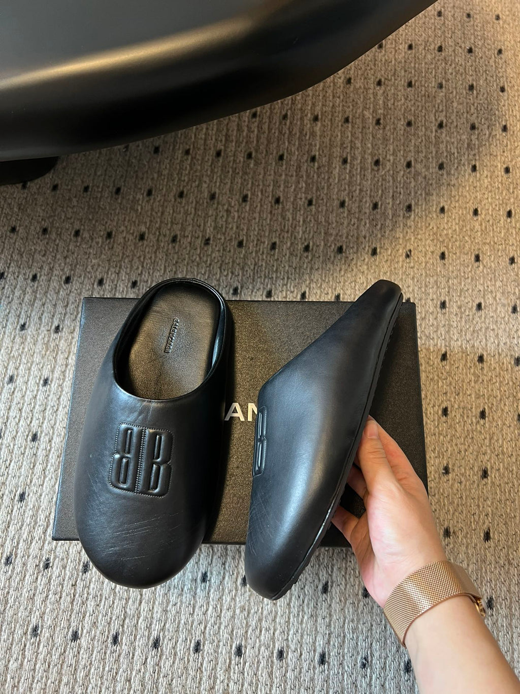 Balenciaga logo slide sandals, pair displayed with one held by a hand