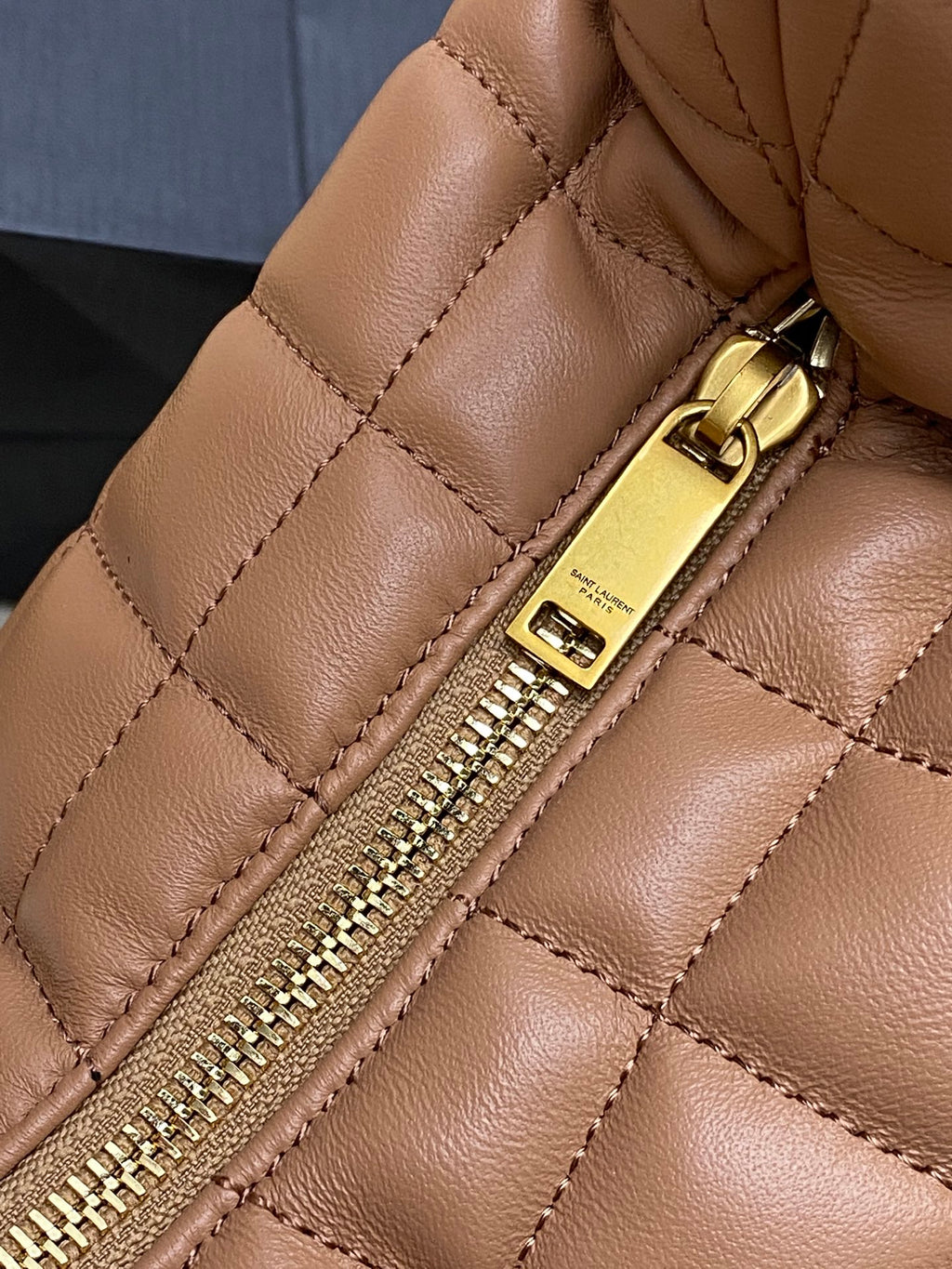 Gold zipper pull on tan quilted leather hobo bag with stitched panel details