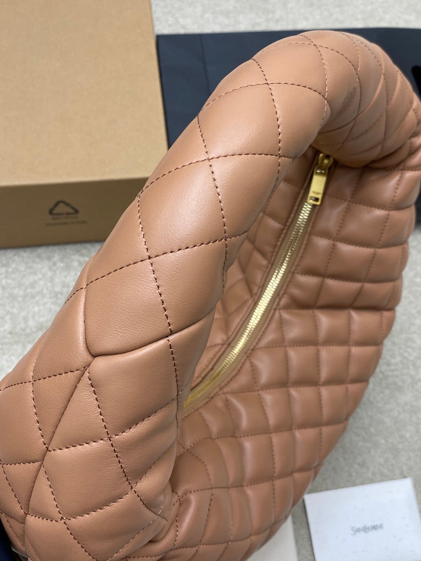 Quilted tan leather hobo bag with gold zipper, padded curved top and handle