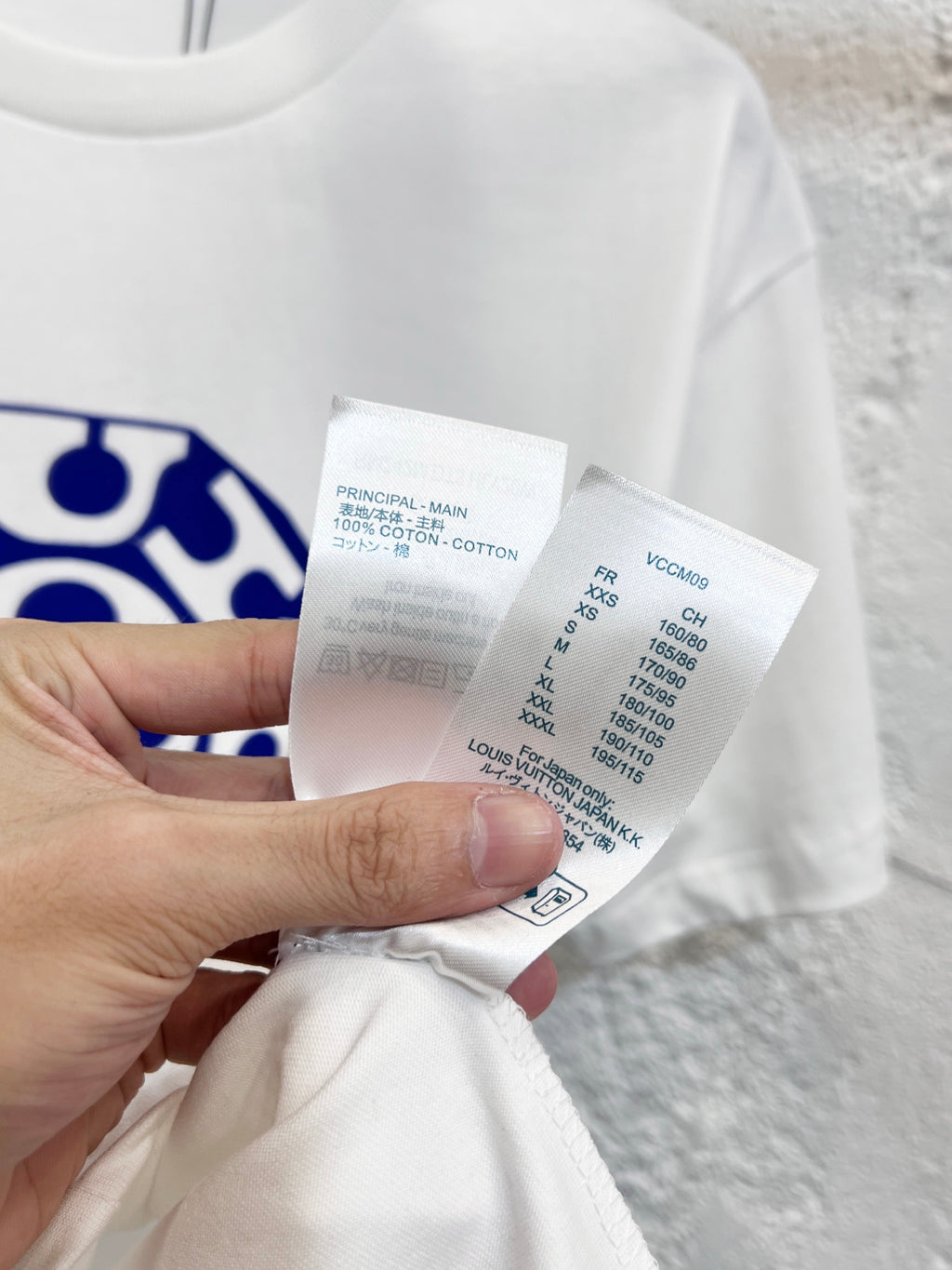 White T-shirt care label and size info tag held in hand