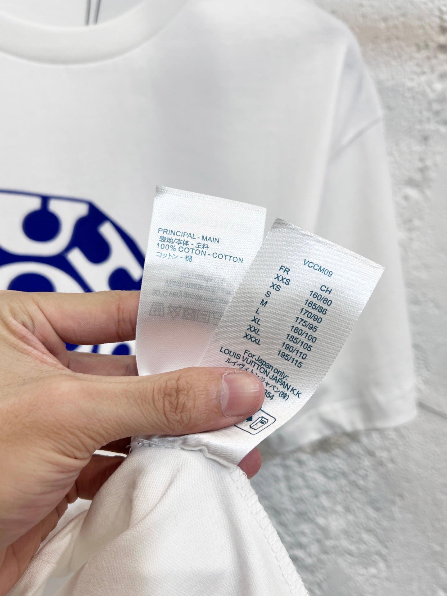 White T-shirt care label and size info tag held in hand