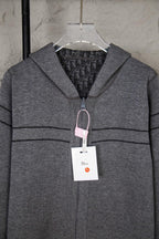 Gray Dior zip hoodie with hood, visible lining, and hanging garment tag