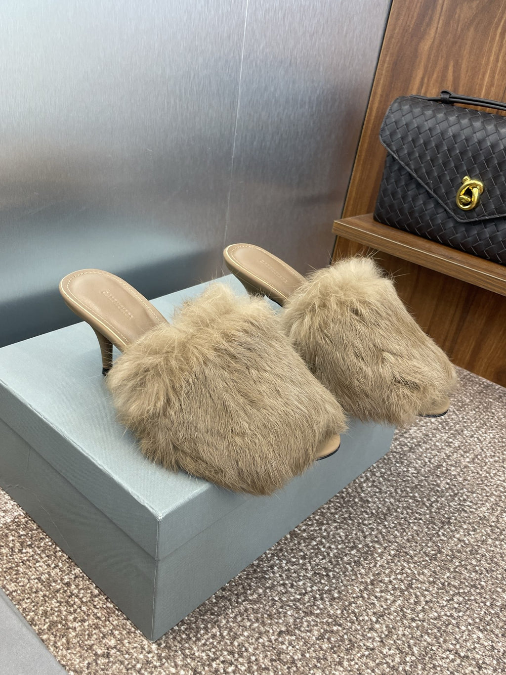 Light beige faux-fur slide sandals with wide band across the foot, on slim heels