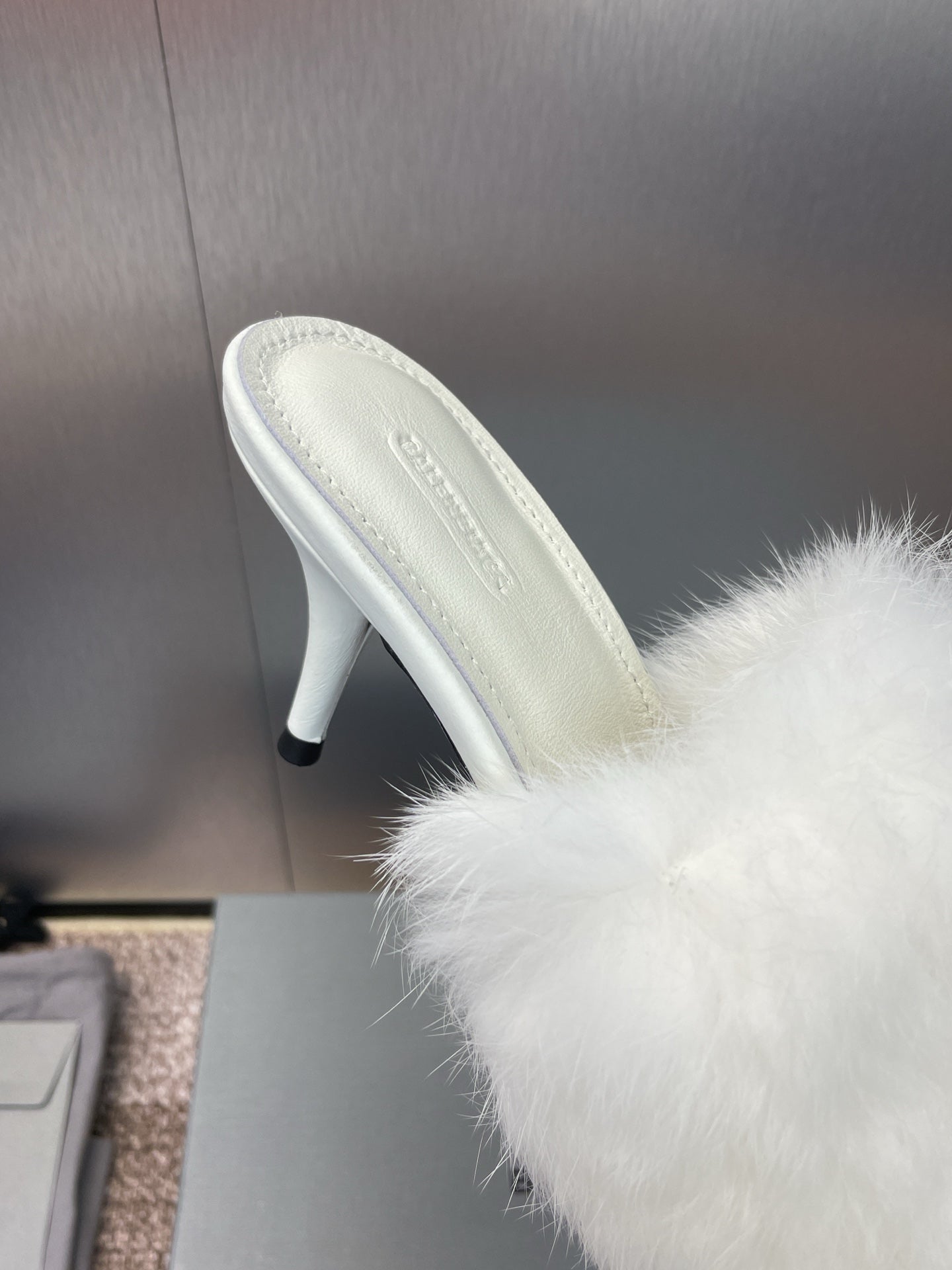 White faux-fur slide sandal with light leather sole and slim stiletto heel.