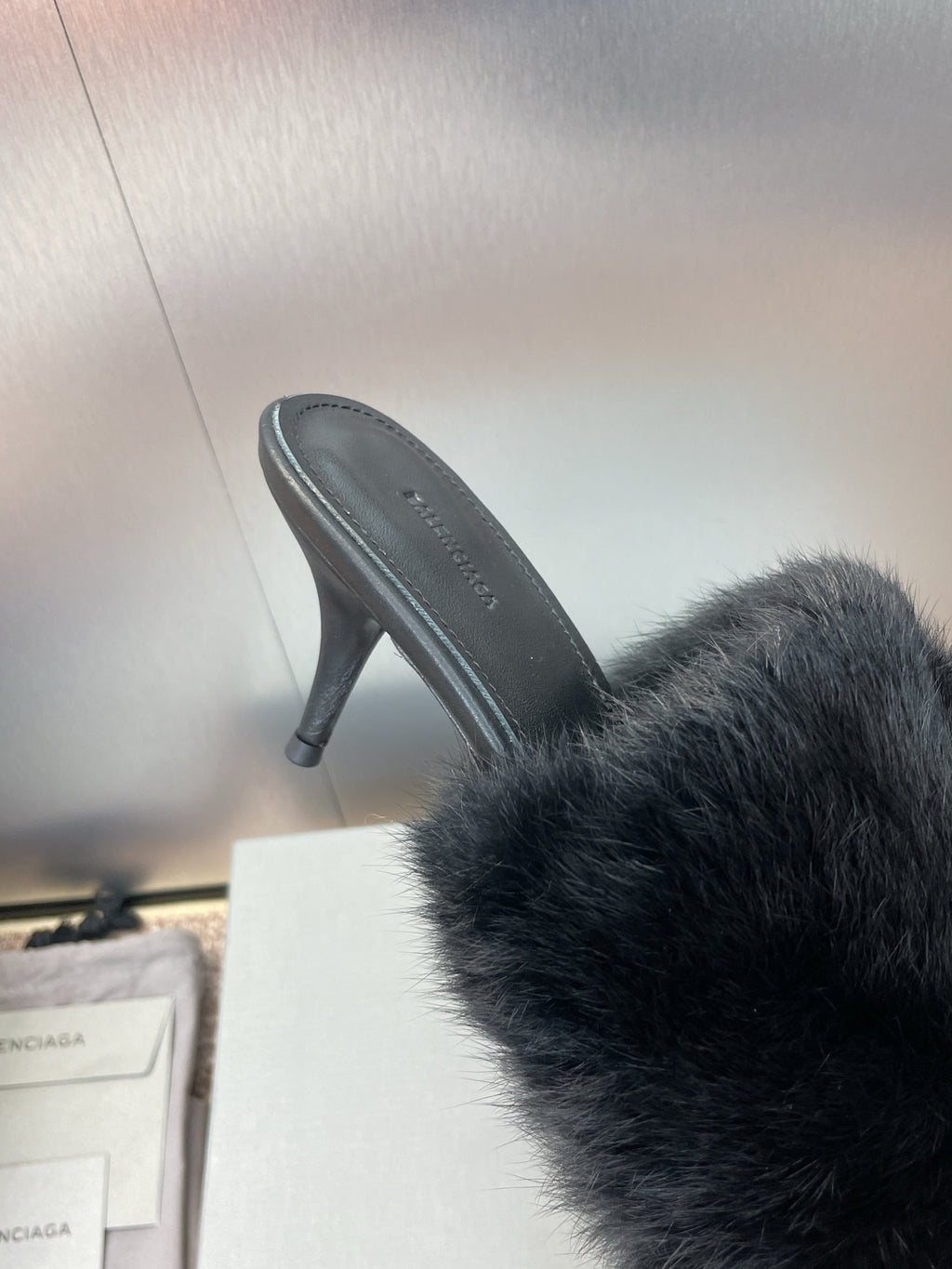 Black faux-fur slide sandal showing side view and stiletto heel.