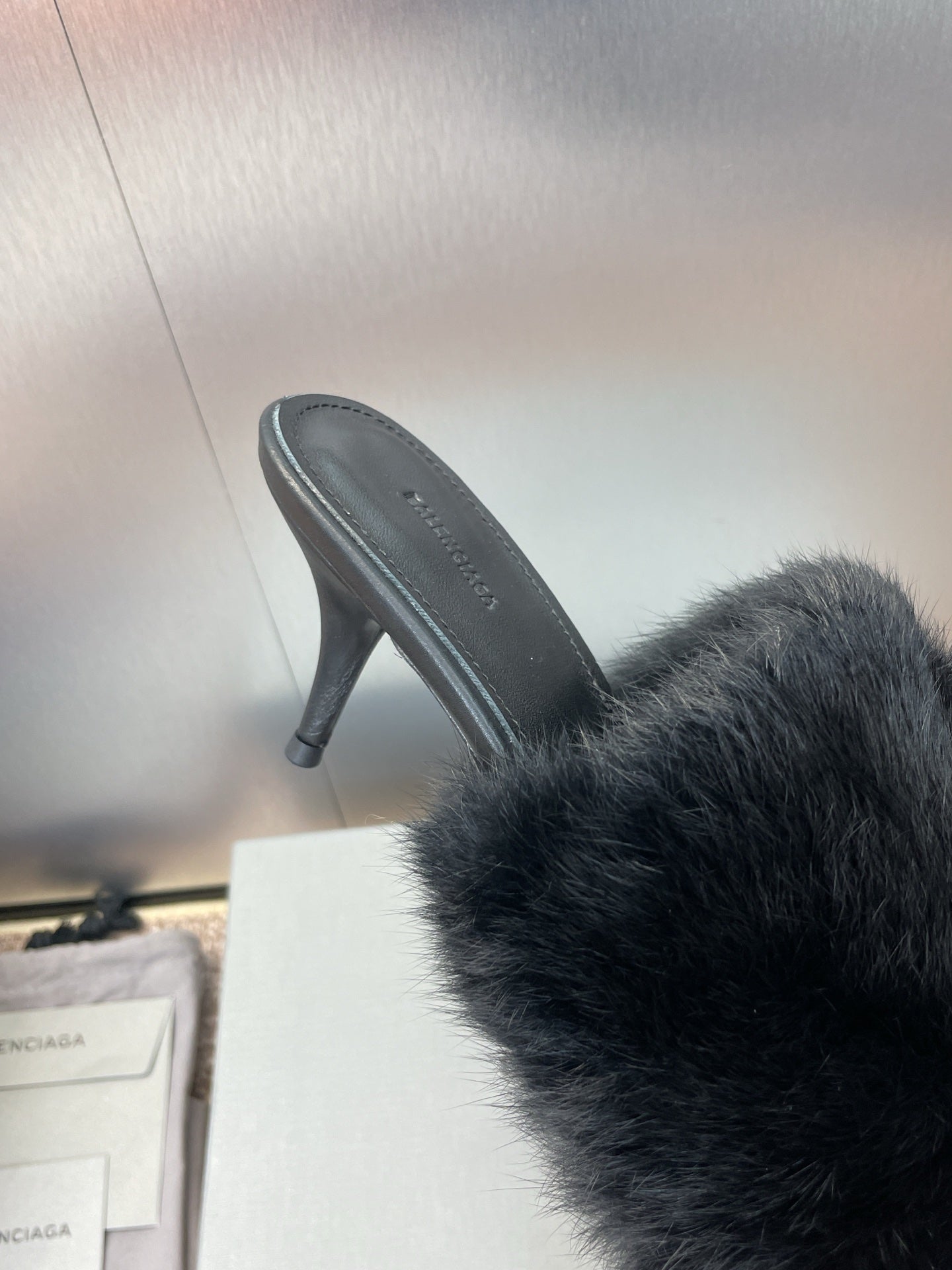 Black faux-fur slide sandal showing side view and stiletto heel.