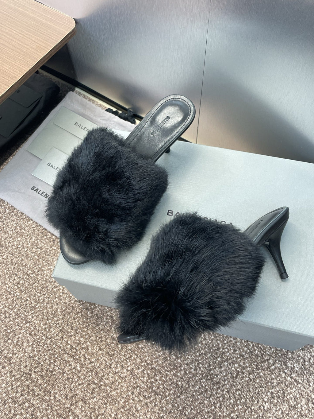 Black faux-fur slide sandals with open toe and tall stiletto heel.