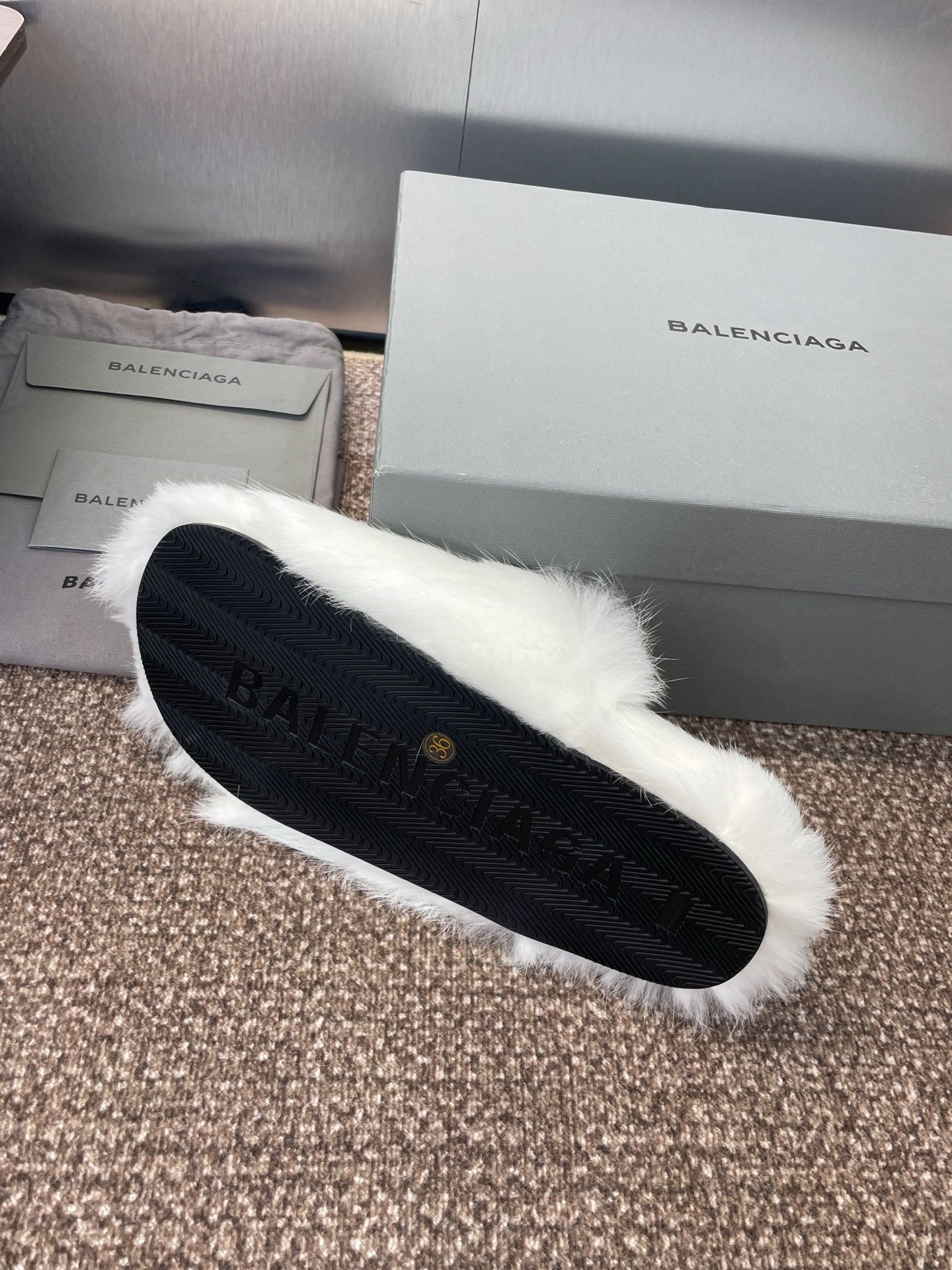 White fur slide sandal with dark rubber sole and textured tread visible