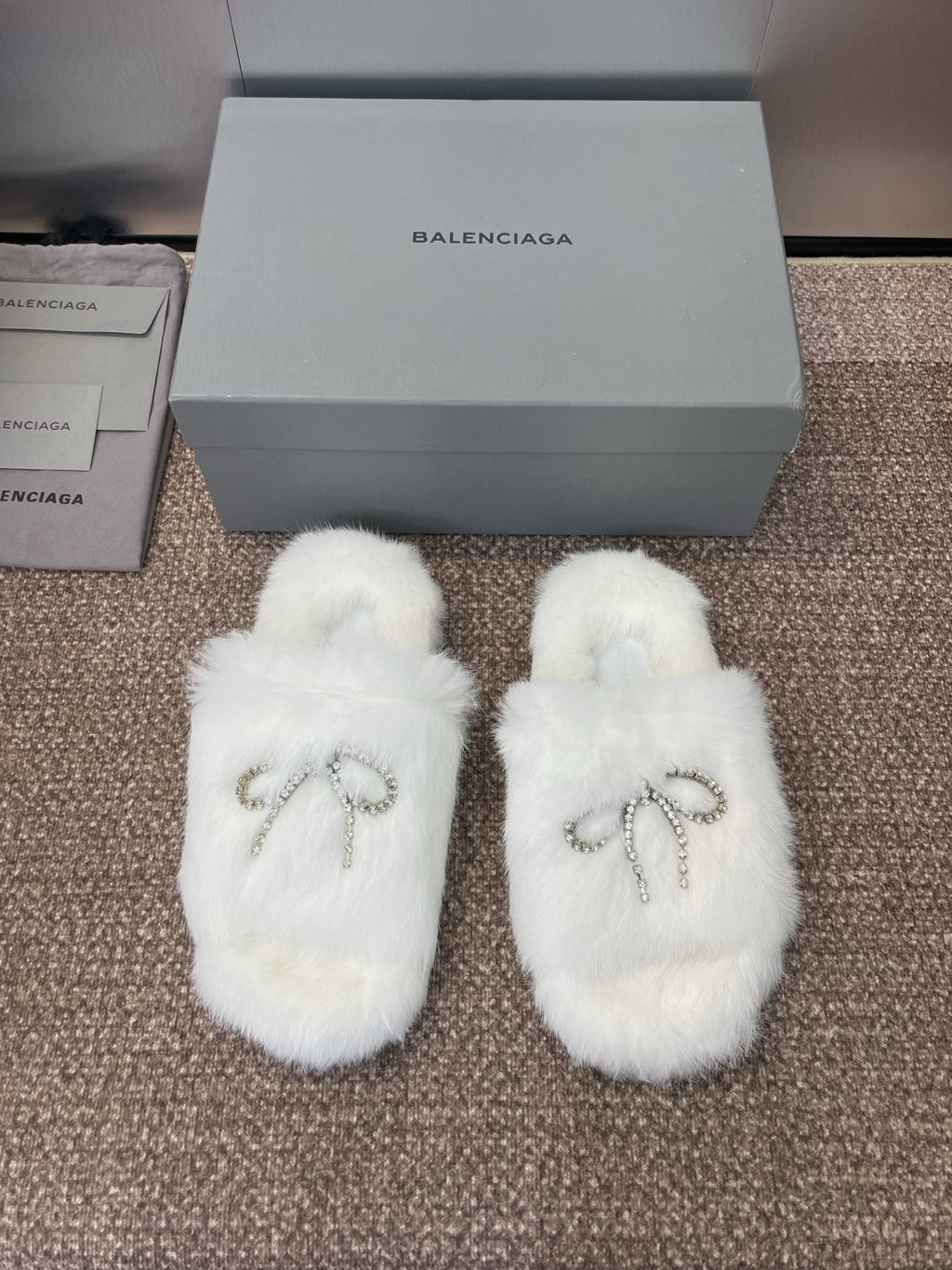 White fluffy slide sandals with rhinestone bow detail on top