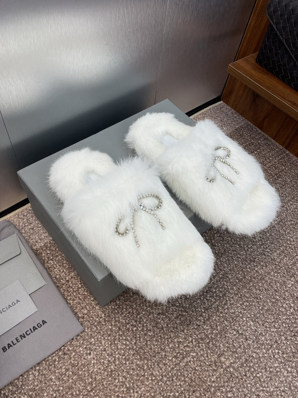 Pair of white furry slide sandals with rhinestone bow embellishment on top