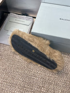 Tan fur slide sandal with dark rubber sole and stitched logo detail