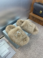 Fuzzy tan slide sandals with rhinestone bow detail across the front
