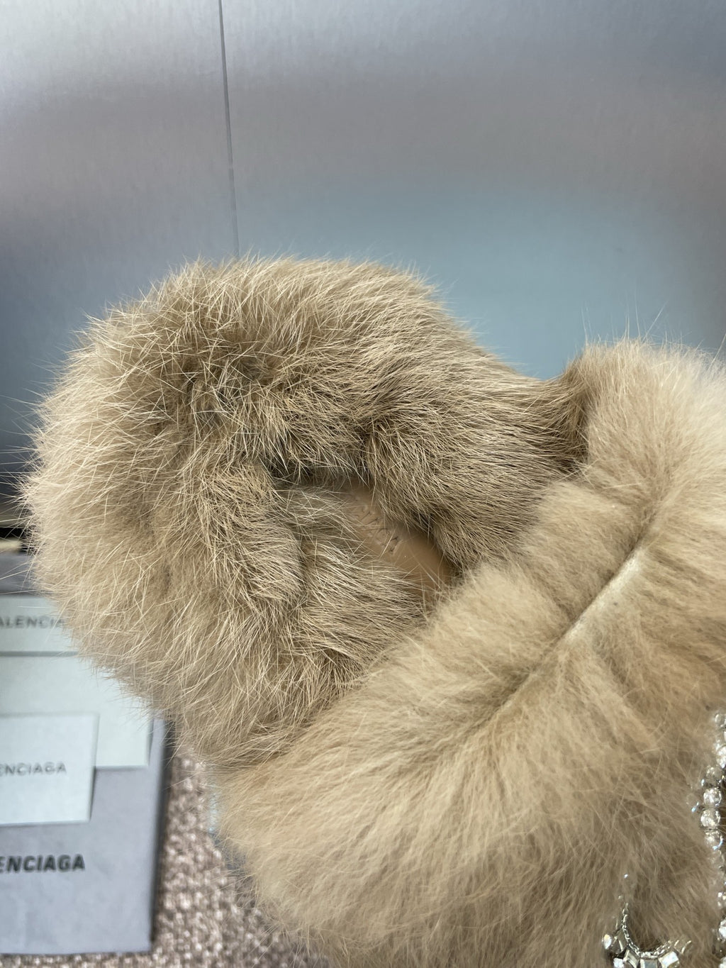 Close-up of tan fuzzy slide sandal with rhinestone bow on the front