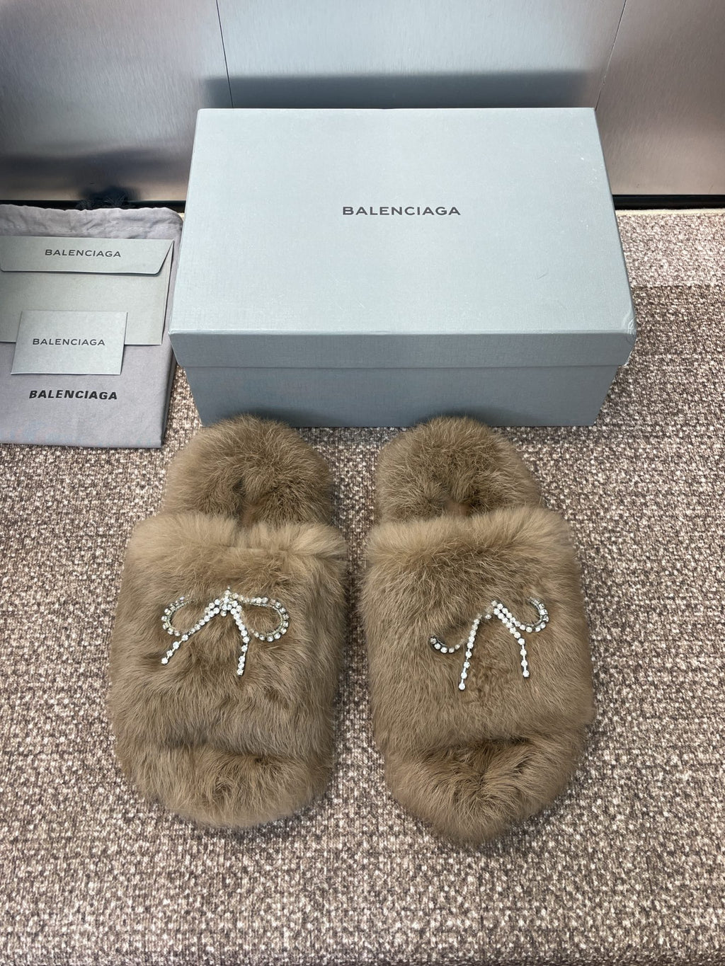 Tan fuzzy slide sandals with rhinestone bow charm on the front