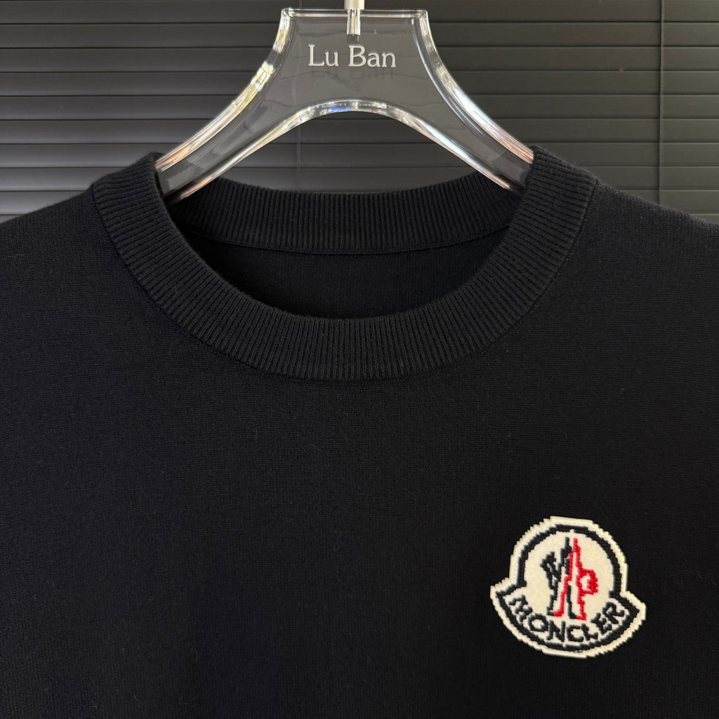 Black Moncler sweater neckline with ribbed collar and embroidered chest logo patch