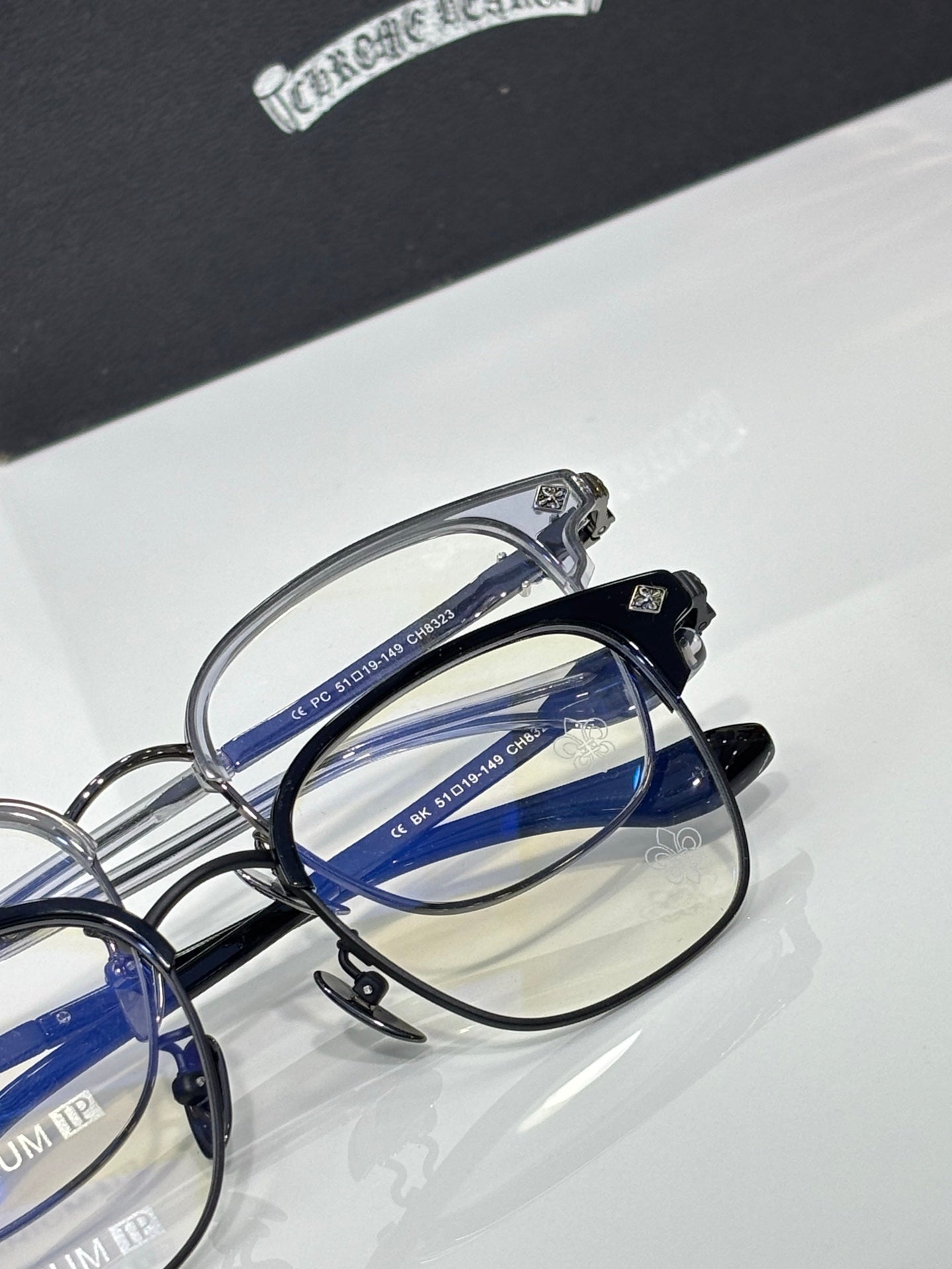 Close-up of chrome eyeglass frame with blue lens sections and metal hinge