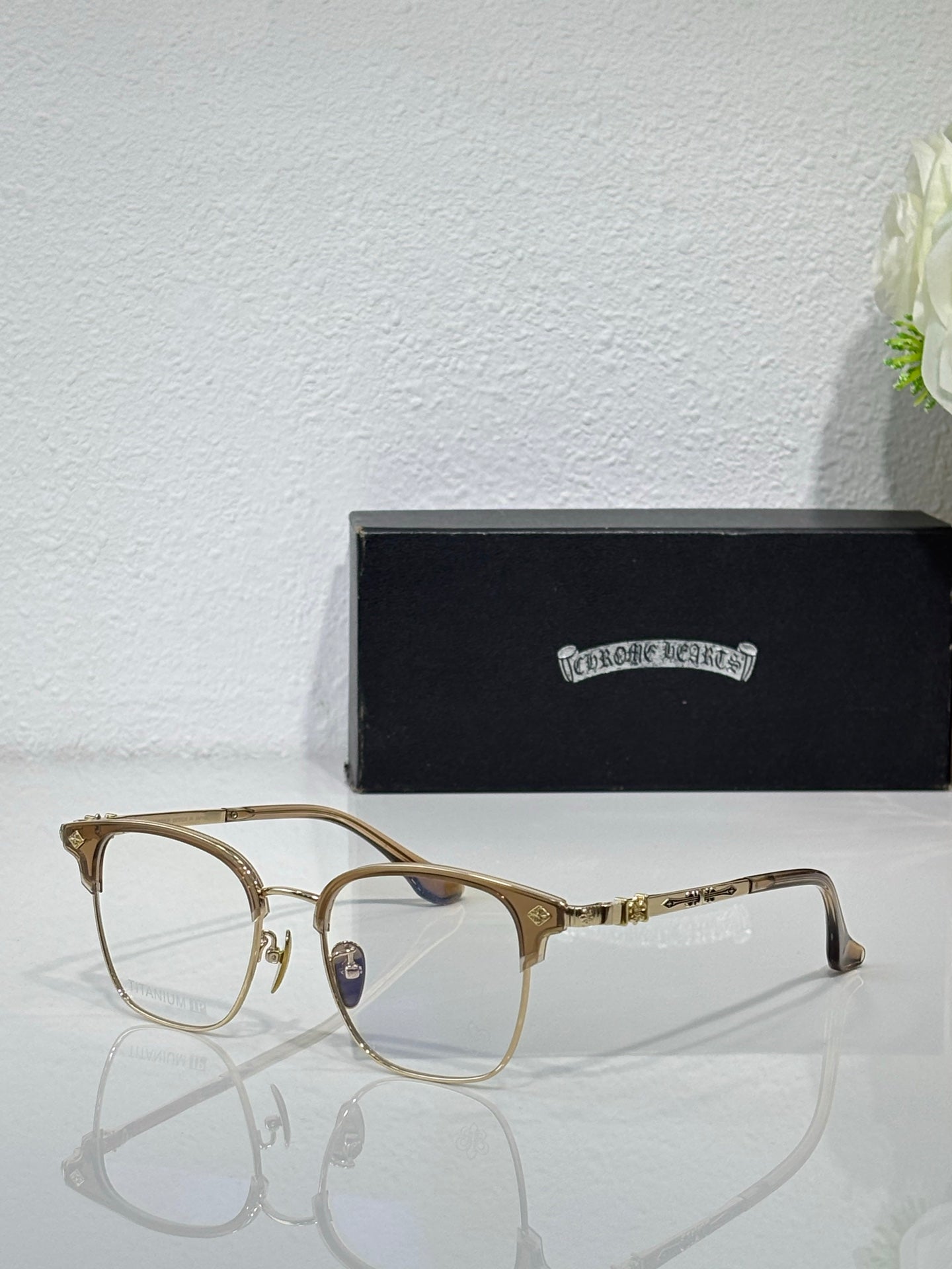 Chrome eyeglasses with gold rectangular frames and clear lenses, angled side view