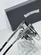 Close-up of chrome eyeglasses with silver frames and ornate hinge detail