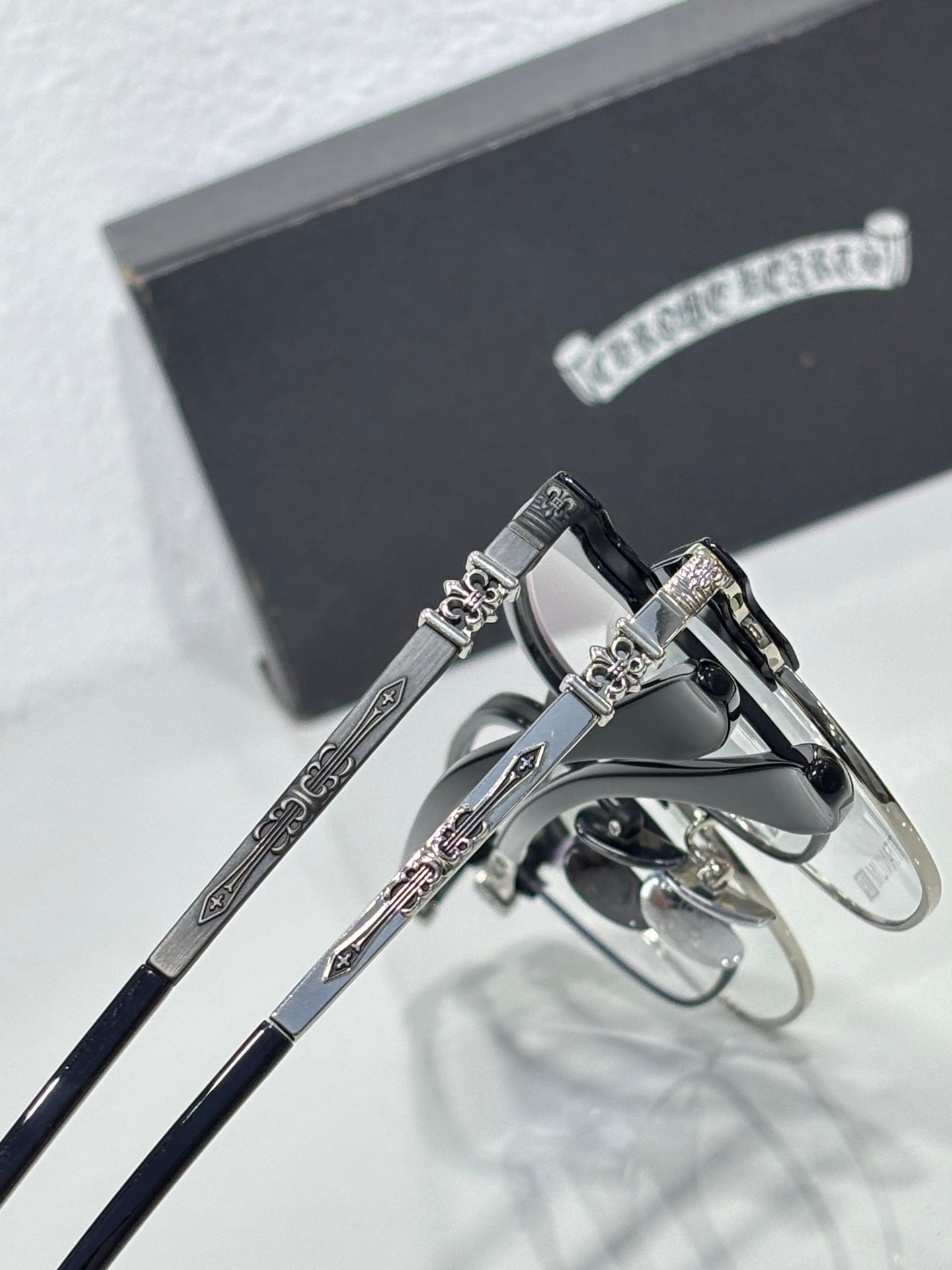 Close-up of chrome eyeglasses with silver frames and ornate hinge detail