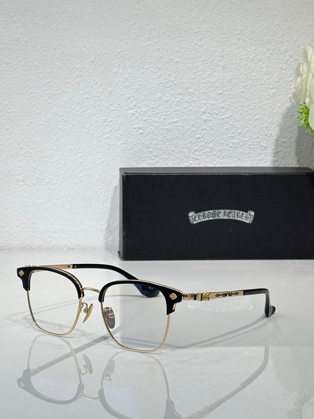 Chrome eyeglasses with gold-tone frames, clear lenses, and blue temple accents