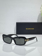 Balenciaga sunglasses with black frames and dark gray lenses, gold logo on temples
