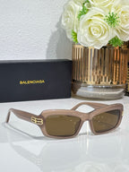 Balenciaga sunglasses with light tan frames and brown lenses, gold logo on temples