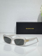 Balenciaga sunglasses with white frames and dark gray lenses, gold logo on temples
