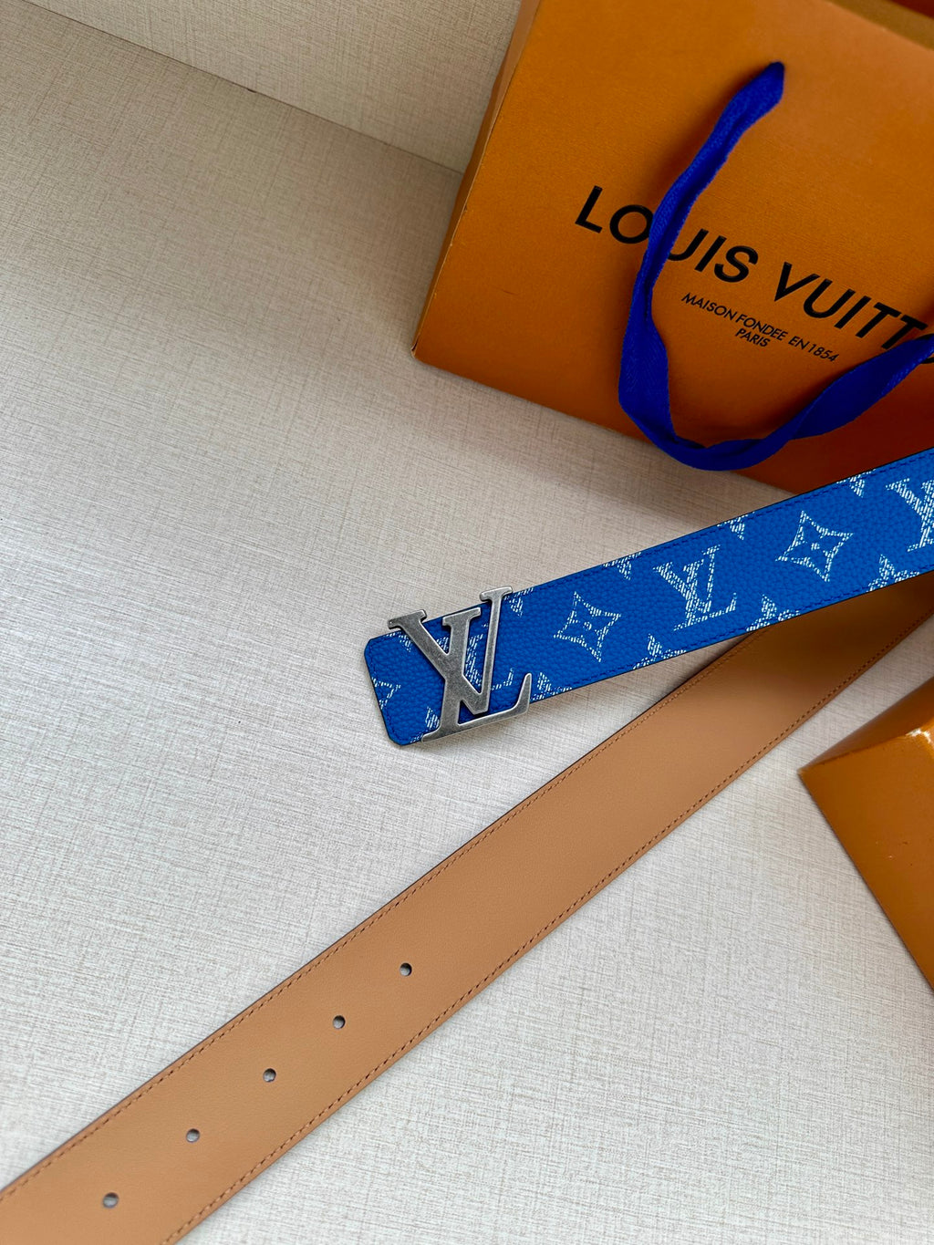 Blue monogram belt with silver LV buckle and tan leather strap, extended