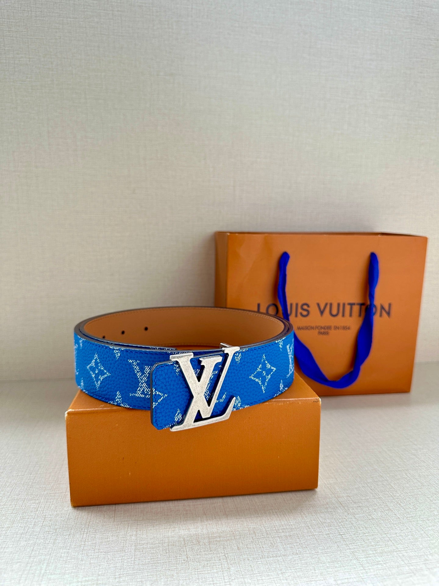 Blue monogram belt with tan leather strap and silver LV buckle, on boxes