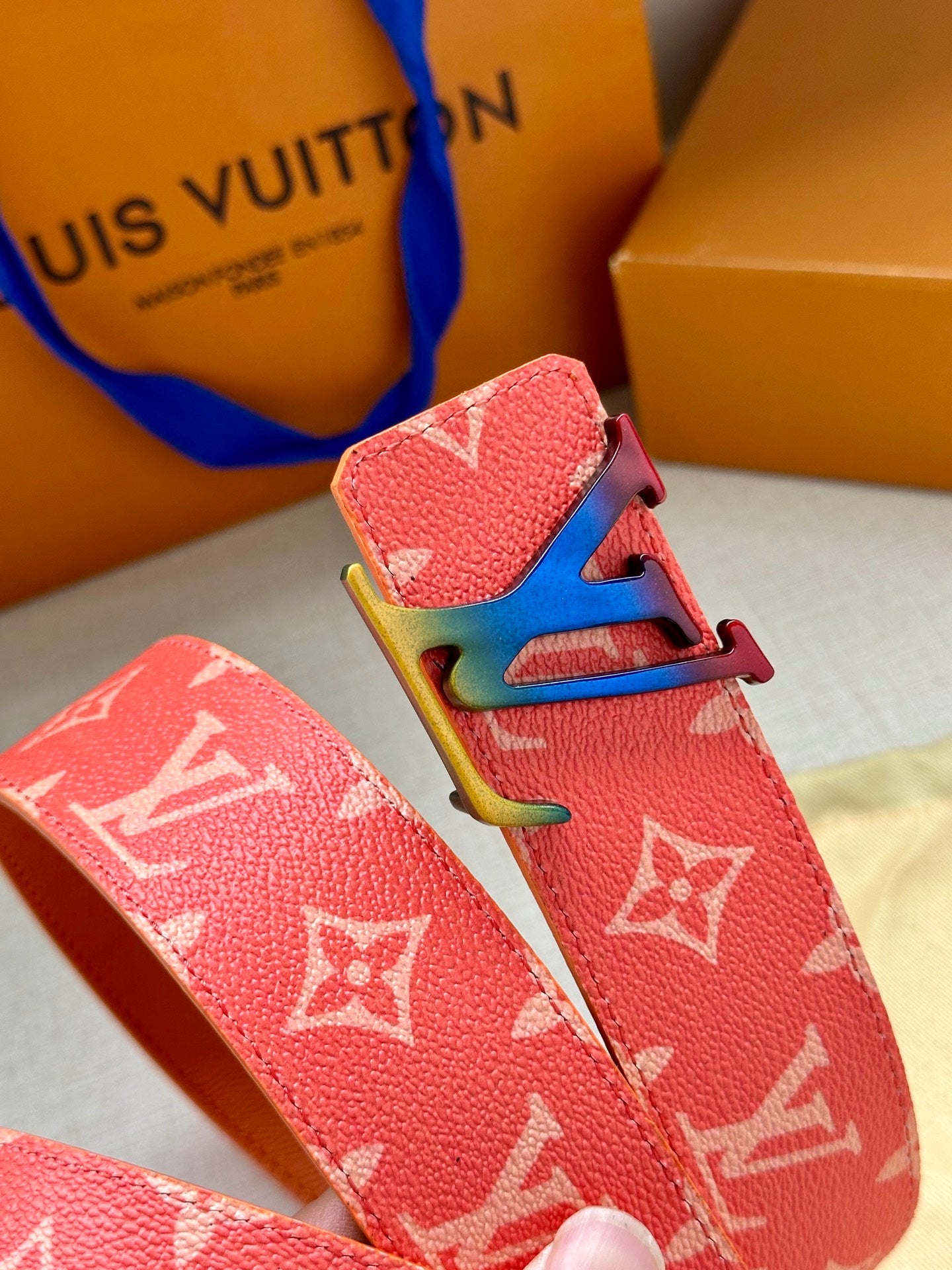 Pink Louis Vuitton monogram belt close-up with gold LV buckle hardware