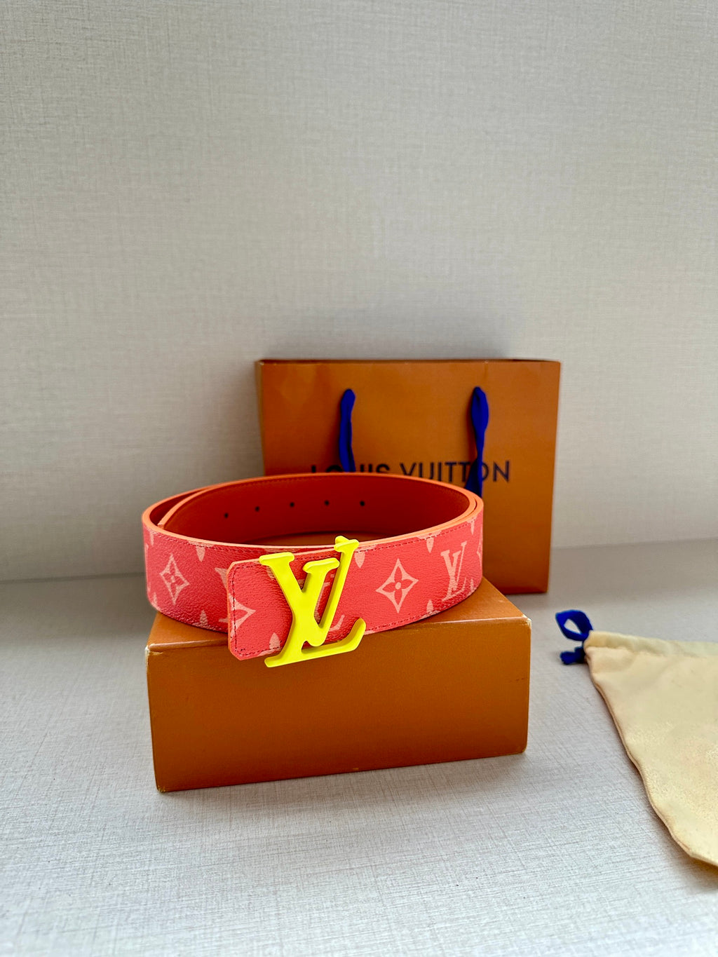 Louis Vuitton belt in red with monogram print and gold-tone LV buckle, shown with box.