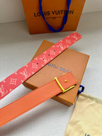 Louis Vuitton belt with red monogram strap and gold-tone LV buckle, laid on box.