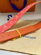 Louis Vuitton belt detail: red monogram strap with gold-tone buckle and orange leather back.