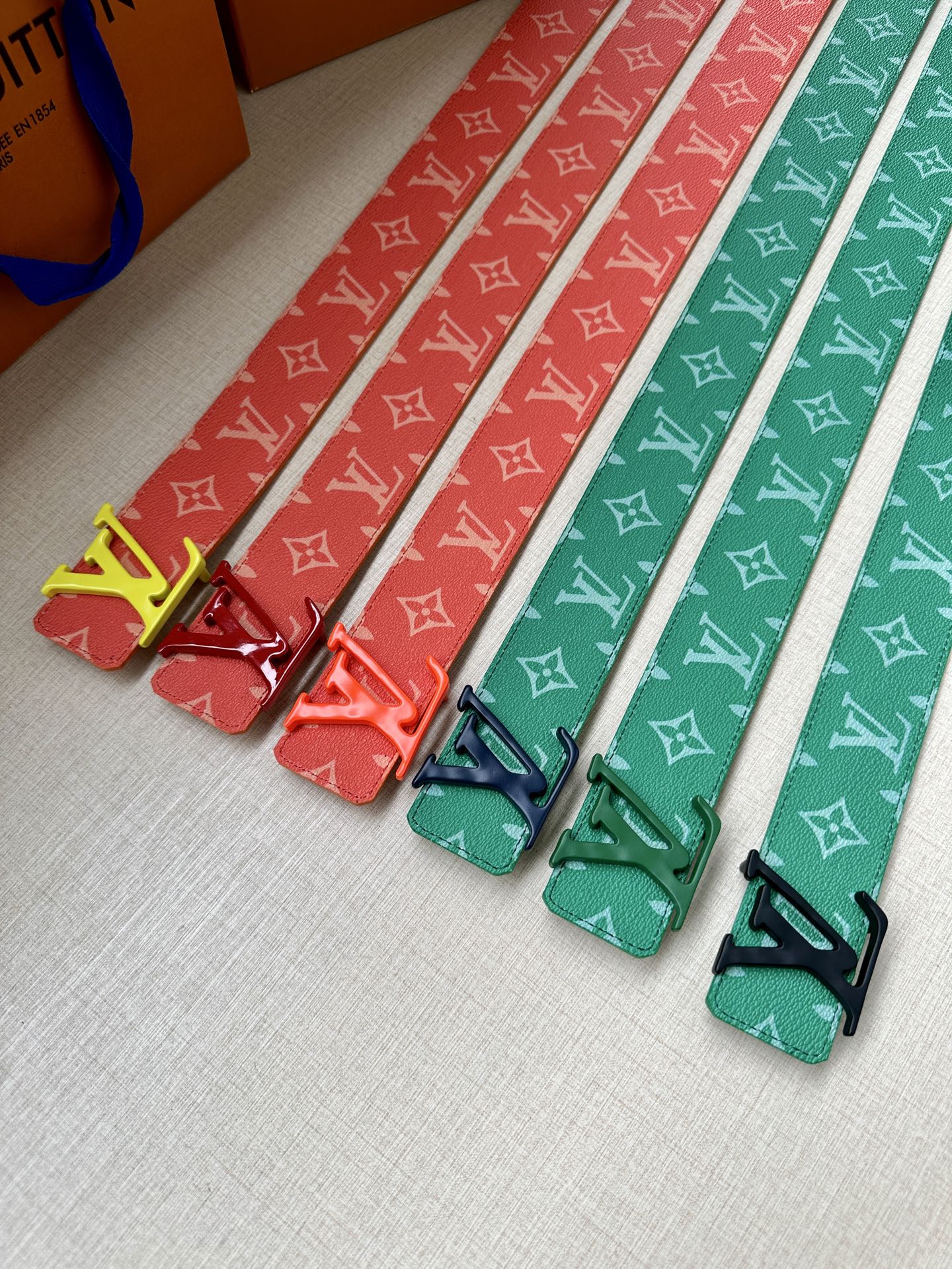 Set of Louis Vuitton belts with monogram straps in red and green tones, with gold buckles.